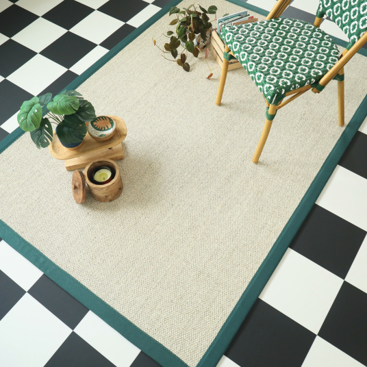 Tapis rectangulaire en sisal Tulum blanchi bordé d'une ganse vert émeraude, dans un intérieur au sol damier noir et blanc