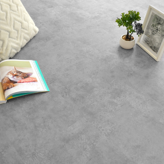 Vue d’ambiance d’un sol en dalles vinyle rigide Performance - Béton marqué, déco zen avec coussin et plante