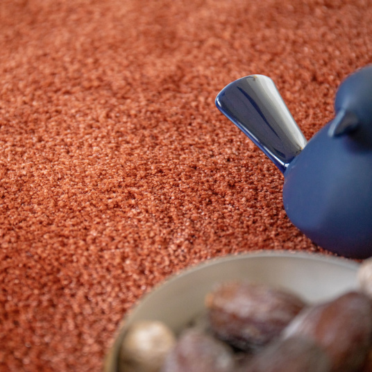 Moquette ultra douce Pulse cuivre brûlé, texture dense avec objet décoratif bleu