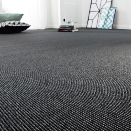 Moquette tissé plat Nusa gris ardoise posée dans un grand espace intérieur lumineux
