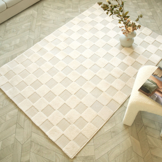 Tapis motif damier Petit Marius crème posé dans un salon lumineux et naturel