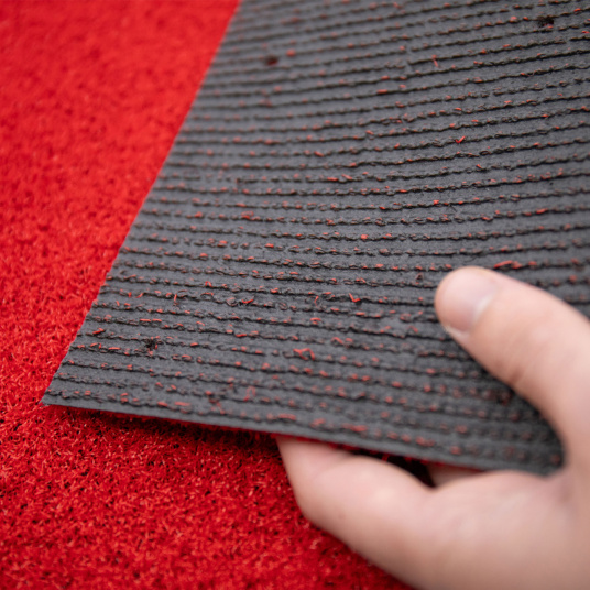 Envers du gazon synthétique Event rouge classé feu Bfl-s1 – main montrant le support