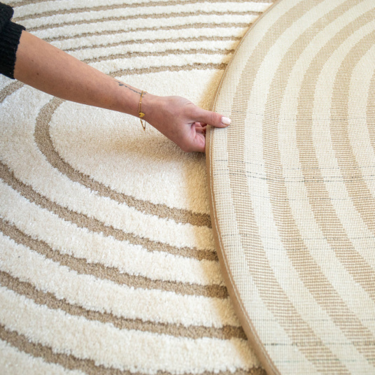 Envers du tapis Circle beige et crème montré en main pour présentation
