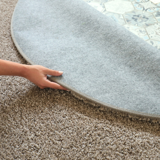 Tapis rond Icône shaggy marron retourné mettant en valeur l’envers feutre et la finition du galon