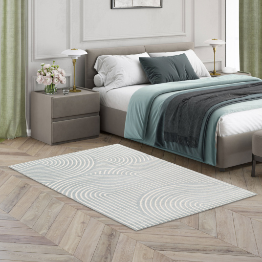 Tapis doux Circle avec courbes graphiques en relief gris bleuté et crème dans une chambre cosy à la déco naturelle