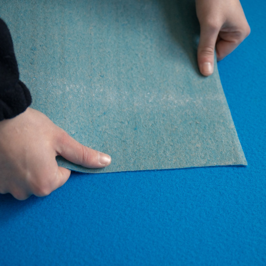 Détail de l'envers de la Moquette Stand Event Bleu azur manipulée pour montrer sa souplesse