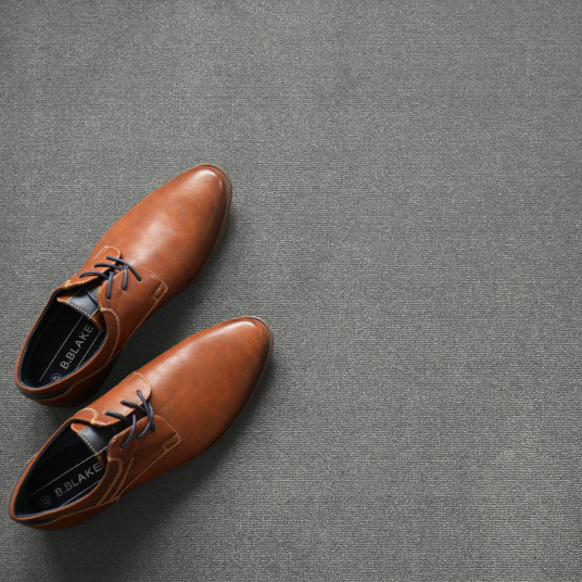 Chaussures en cuir et accessoires décoratifs posés sur un tapis sur mesure Sylon Gris minéral haute résistance