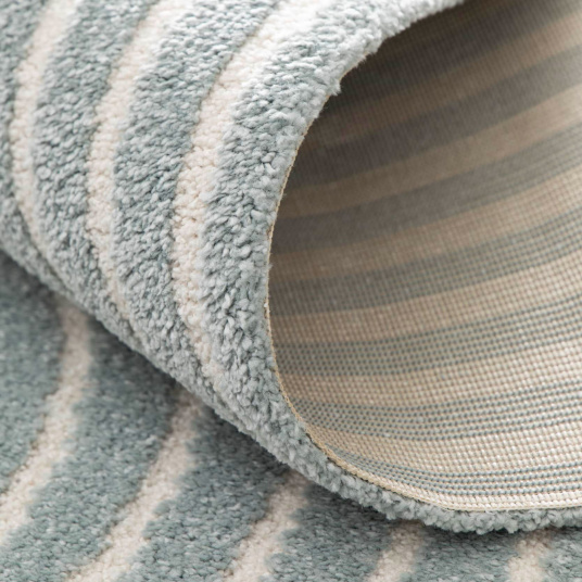 Gros plan sur le tapis en relief Circle, motifs courbes gris bleuté et crème