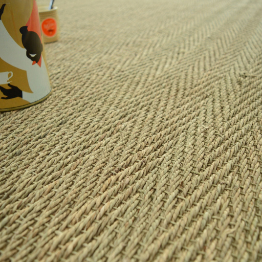 Zoom sur le tissage en chevron du tapis Bihar en jonc de mer, ganse coton beige