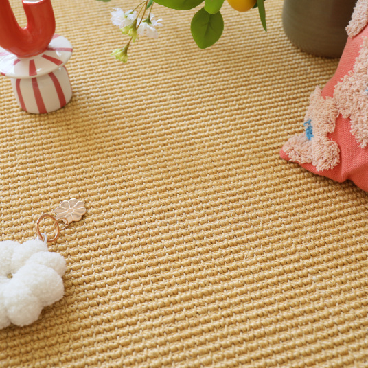 Revêtement en sisal grosses boucles Cancun Naturel avec coussin rose et porte-clé fleur sur fond doux et lumineux
