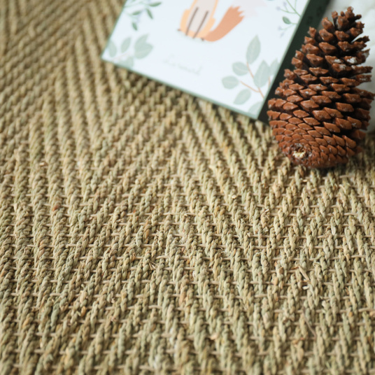 Zoom sur le motif chevron du tapis jonc de mer Assam, aspect brut et authentique avec sa ganse marron glacé