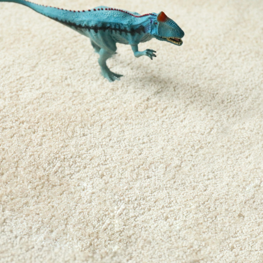 Zoom sur la texture de la moquette Lumicolor beige clair, douce et résistante dans une chambre d’enfant