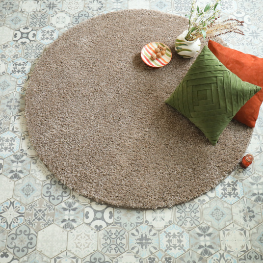 Tapis rond shaggy marron Icône galonné posé dans une pièce de vie avec sol à carreaux décoratifs