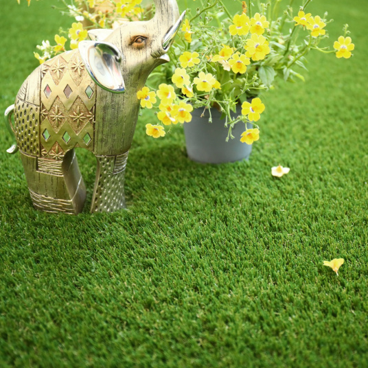 Détail du gazon synthétique Eden 35 mm avec déco florale et éléphant stylisé