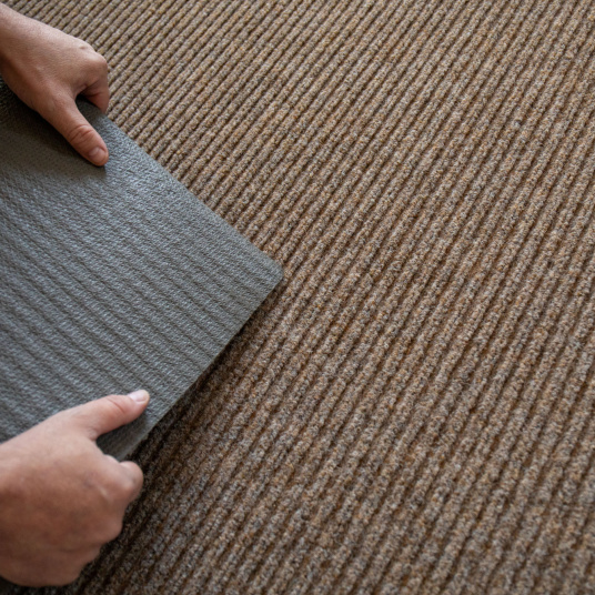 Détail du tapis beige, dos caoutchouc antidérapant et texture côtelée