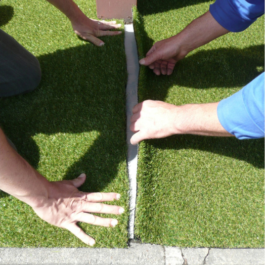 Collage du gazon synthétique sur la bande de jonction autocollante