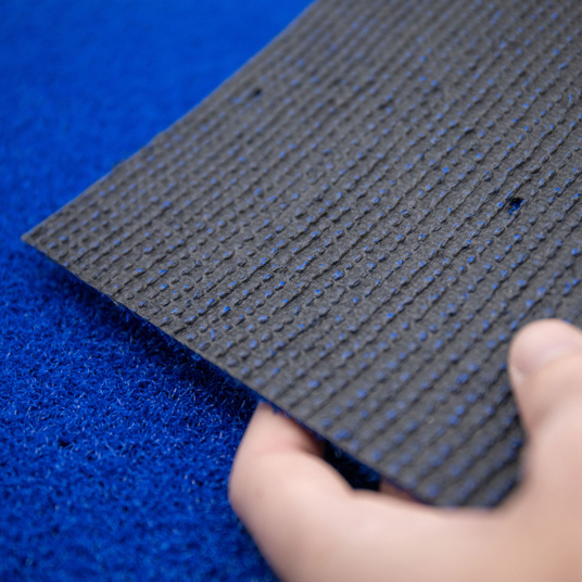 Zoom sur le dessous du gazon Event bleu 8 mm  classé feu – main tenant le revêtement