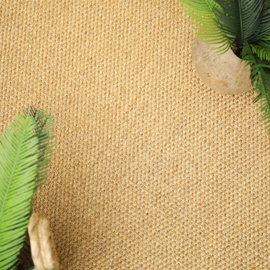 Vue de dessus sur le revêtement de sol en sisal Tulum miel, décoré de feuillage tropical
