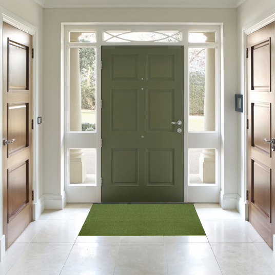 Tapis sur mesure Paillasson Brosse Coco 23 mm - Vert Pomme, disposé devant une porte d'entrée vert grisé dans un hall classique aux boiseries blanches