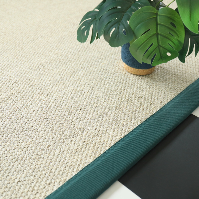 Tapis sur mesure en sisal Tulum blanchi avec ganse vert émeraude, vue en perspective sur sol damier noir et blanc