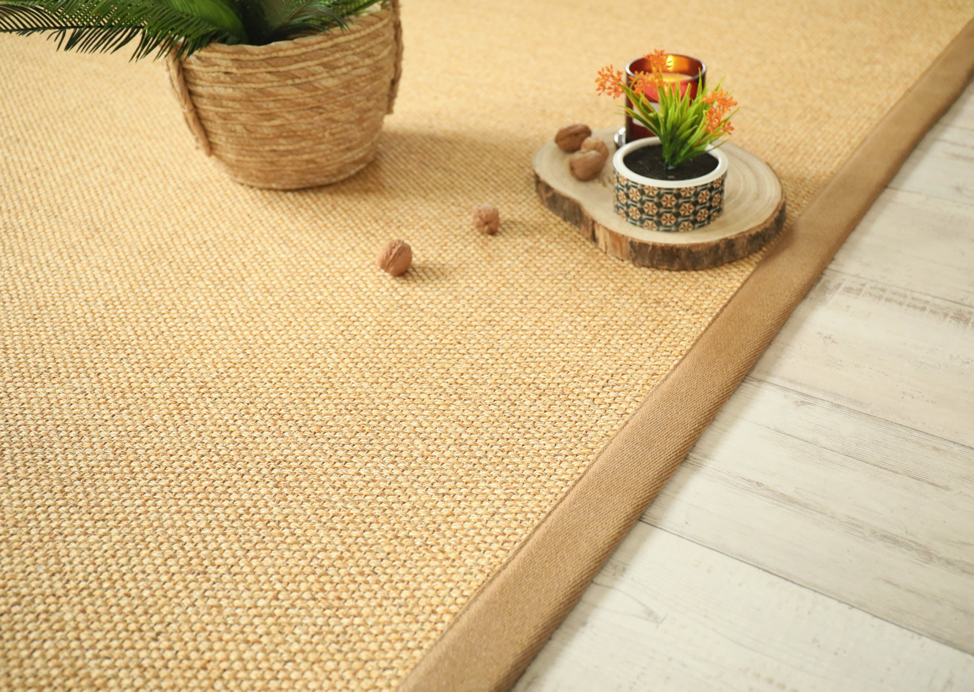 Zoom sur la texture du tapis en sisal Tulum coloris miel avec assiette en bois et fruits oranges